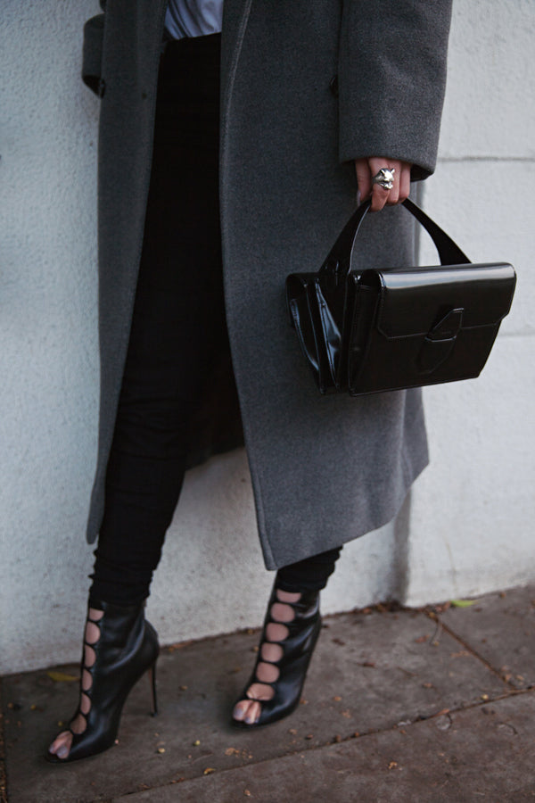 Woman in a grey coat and lace-up heels holding a black handbag, wearing the silver Lioness ring