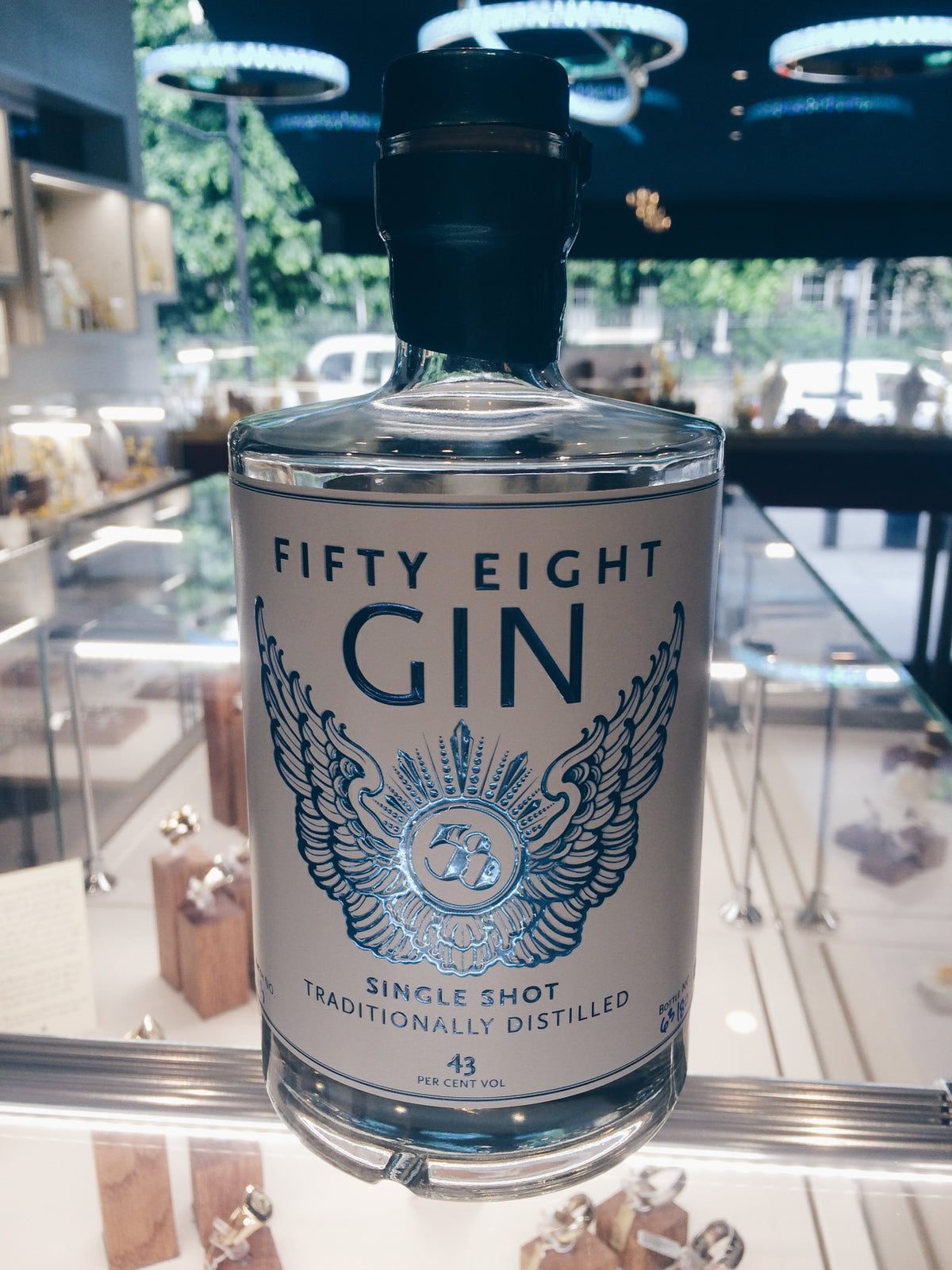 Bottle of Fifty Eight Gin standing on a glass jewellery counter in our shop