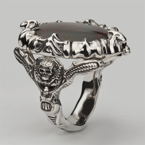 Bespoke silver skull and bones ring with a large oval dark red stone held in a sculpted bone setting