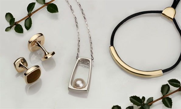 Gold cufflinks, a silver pendant framing a white pearl and a gold bar bracelet on black cord, with holly sprigs