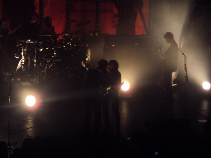 The Libertines on stage under smoky backlighting, with the drum kit and guitarists in silhouette