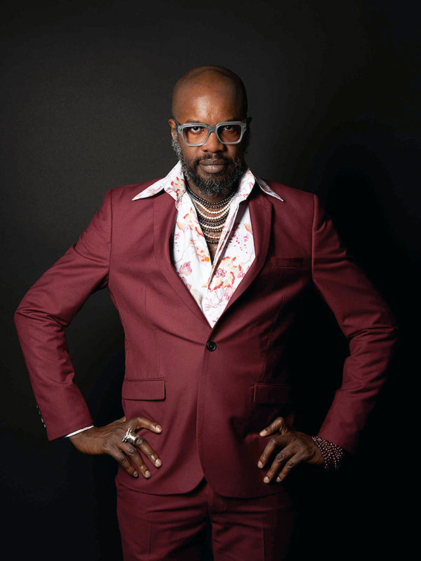 David McAlmont in a burgundy suit and floral shirt, wearing layered necklaces and a silver ring