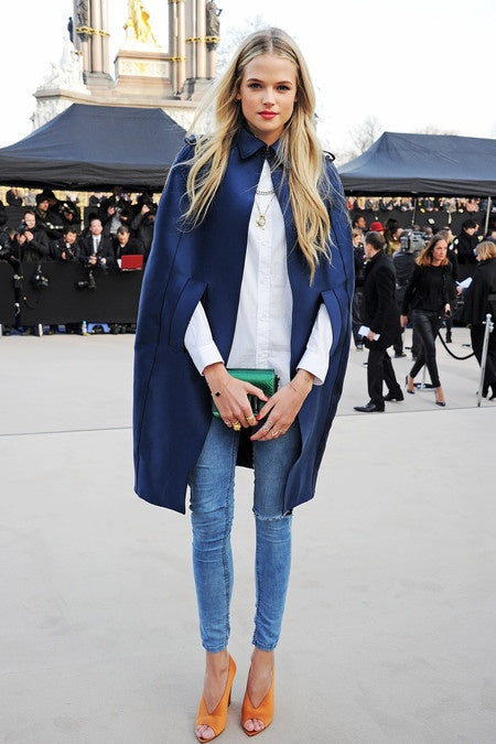Woman at London Fashion Week in a navy cape and white shirt with layered gold necklaces