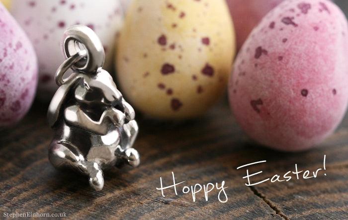 Silver bunny charm in front of speckled pastel mini eggs, with the words "Hoppy Easter!"