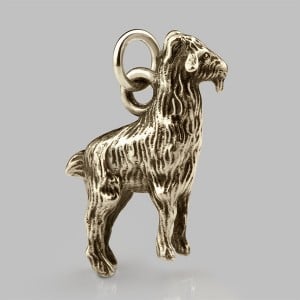 Gold goat charm with a finely textured coat on a jump ring, against a grey background