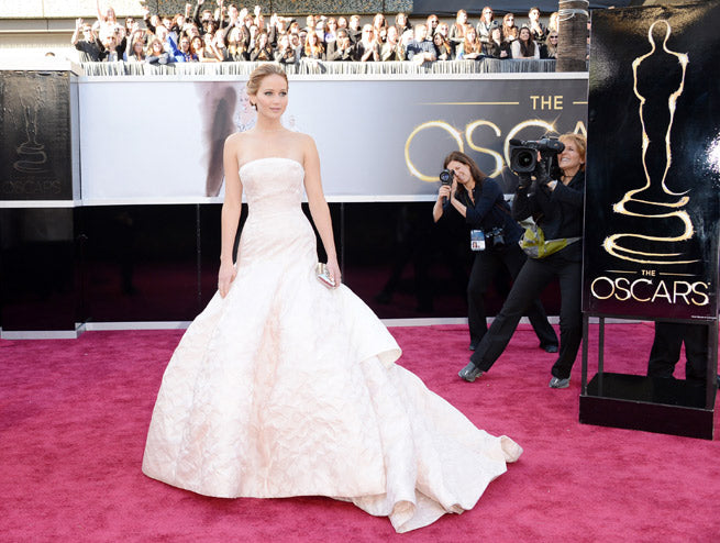 Jennifer Lawrence in a strapless pale pink ball gown on the red carpet at the 2013 Oscars