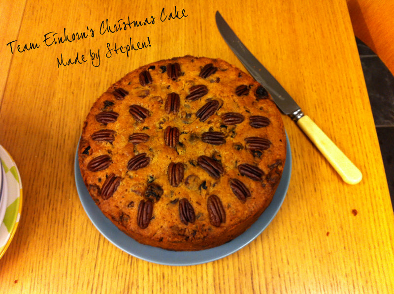 Pecan-topped Christmas cake on a blue plate with a knife, captioned as made by Stephen for the team