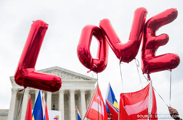 Red foil balloons spelling LOVE and flags held up outside the US Supreme Court