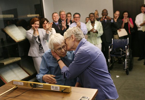 Two elderly women embrace after exchanging wedding vows in New York as onlookers applaud