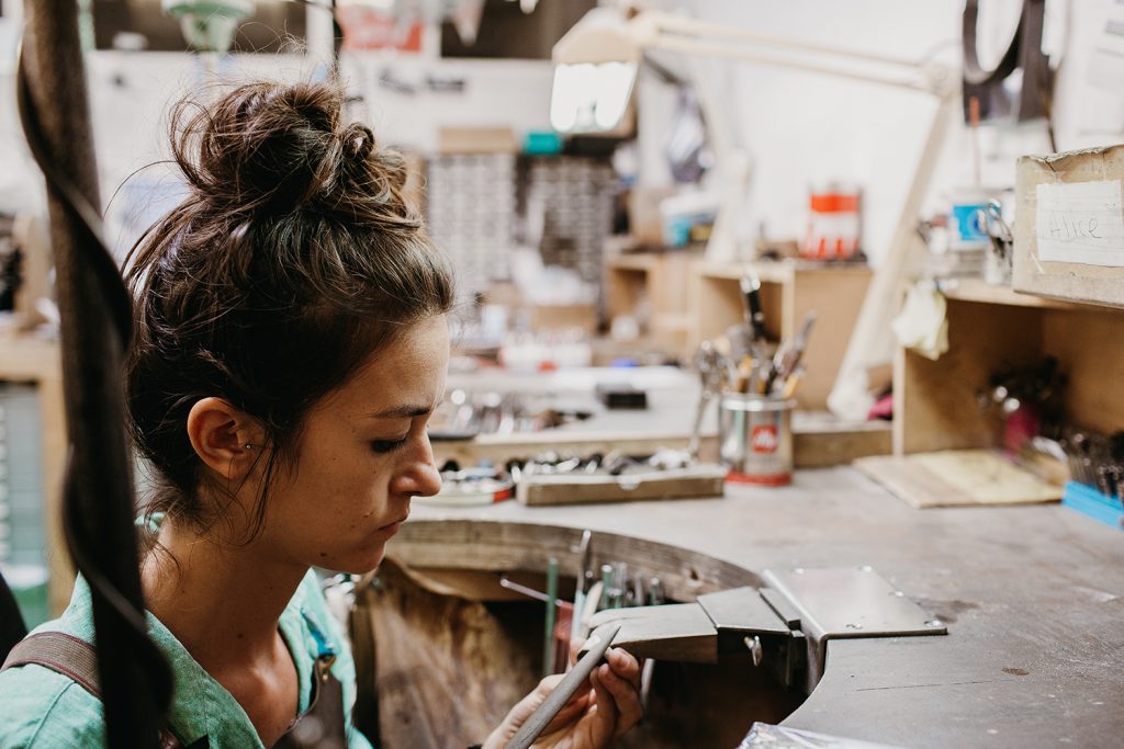 Jeweller with her hair tied up working at the bench in our Islington workshop
