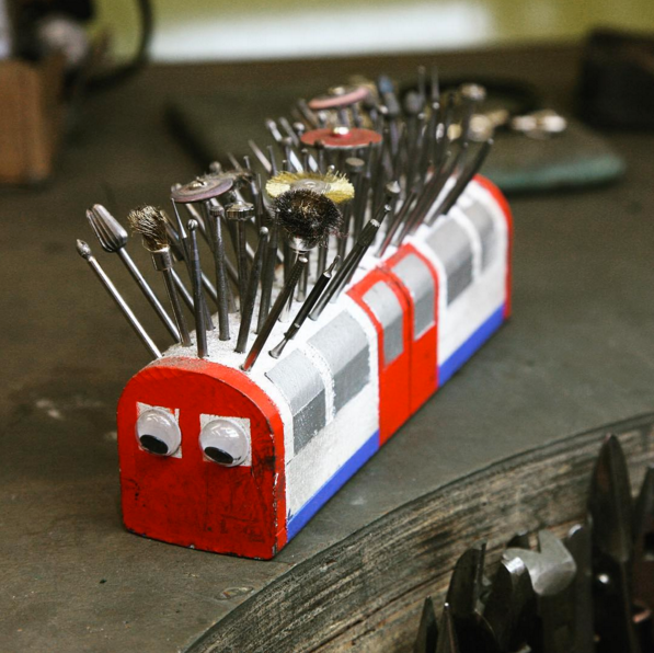 Workshop tool holder painted as a London Underground train with googly eyes, full of burrs and polishing bits