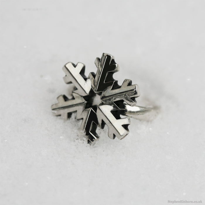 Silver snowflake ring with six sculpted points, resting in fresh white snow