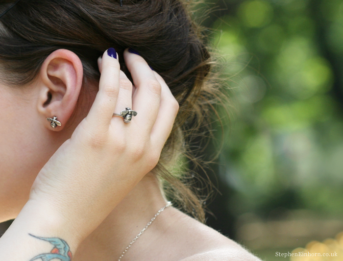 Woman touching her hair, wearing silver bee stud earrings and a silver bee ring