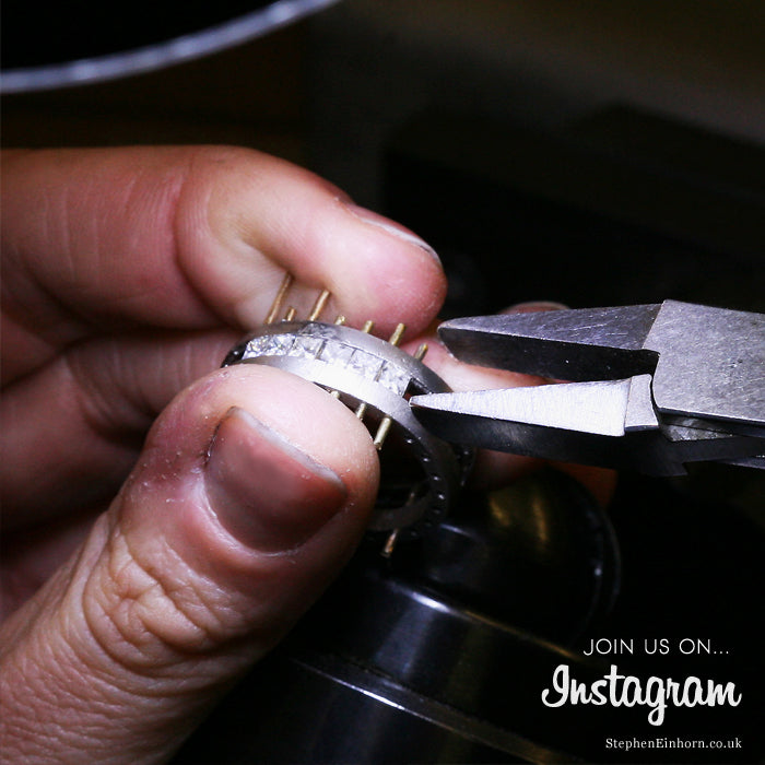 Jeweller holding a men's Geo diamond eternity ring with pliers while setting the stones in our London workshop