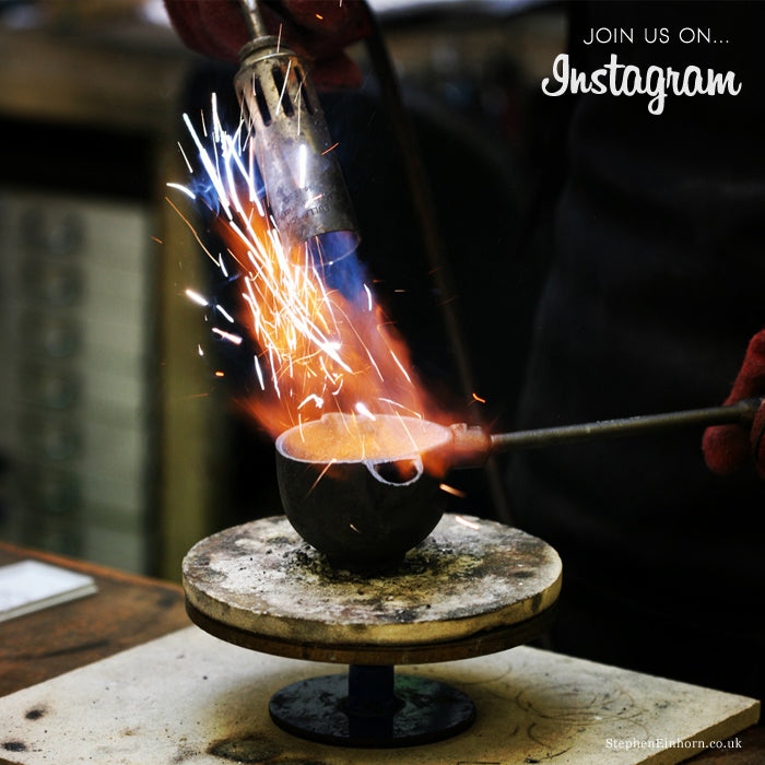 Sparks and flames from a blowtorch melting metal in a crucible in our workshop, with an Instagram caption
