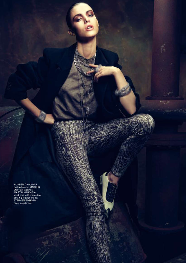 Departures magazine fashion shoot of a model in a black coat wearing layered silver necklaces and silver cuffs