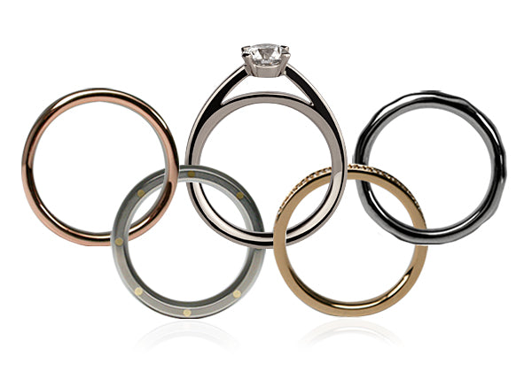 Five rings arranged as the Olympic rings: rose, white and yellow gold and black bands and a diamond solitaire