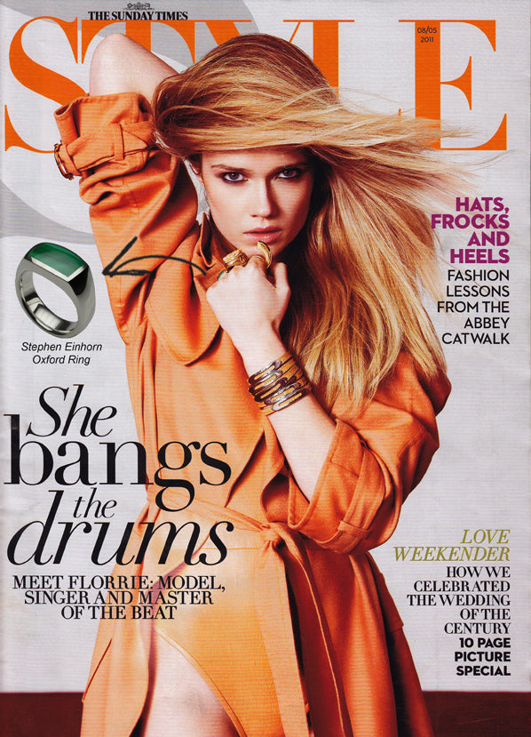 Sunday Times Style cover of a model in an orange trench coat, with an inset of the Oxford ring with a green stone