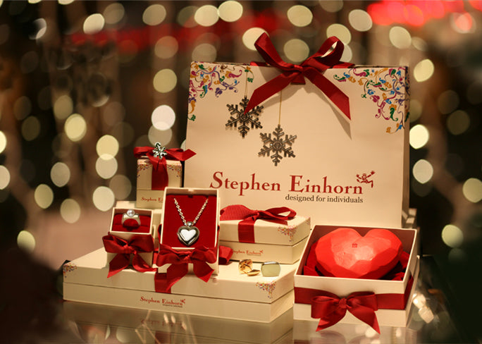 Stephen Einhorn gift boxes with red ribbons holding a heart pendant, rings and snowflake charms