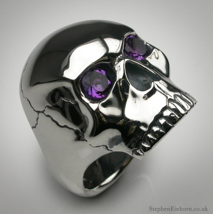 Polished silver skull ring with purple amethyst eyes and a cracked cranium detail