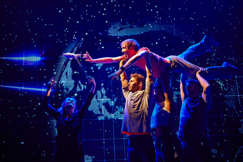 Actors lifting a boy through the air against a starry backdrop in The Curious Incident of the Dog in the Night-Time