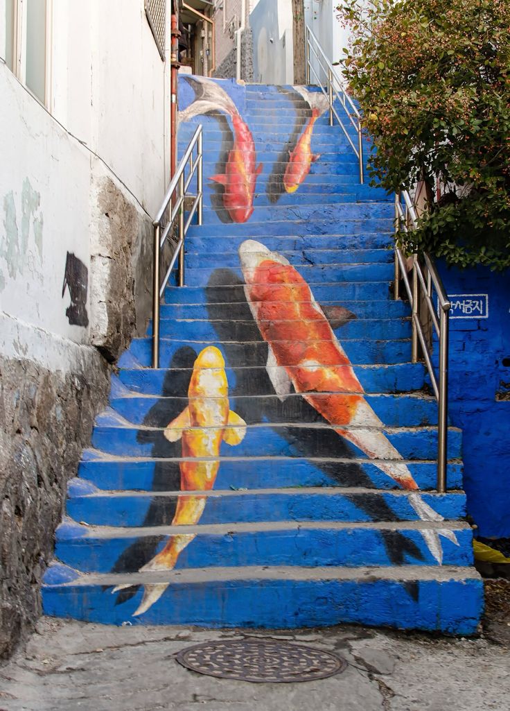 Outdoor stairway painted blue with large orange and gold koi carp swimming up the steps