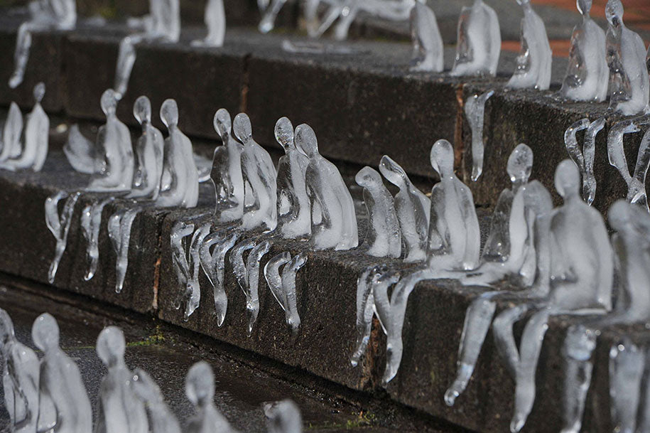 Hundreds of small melting ice figures seated on steps, part of Néle Azevedo's Minimum Monument