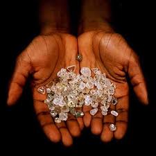 Cupped hands holding a pile of rough uncut diamonds of different sizes