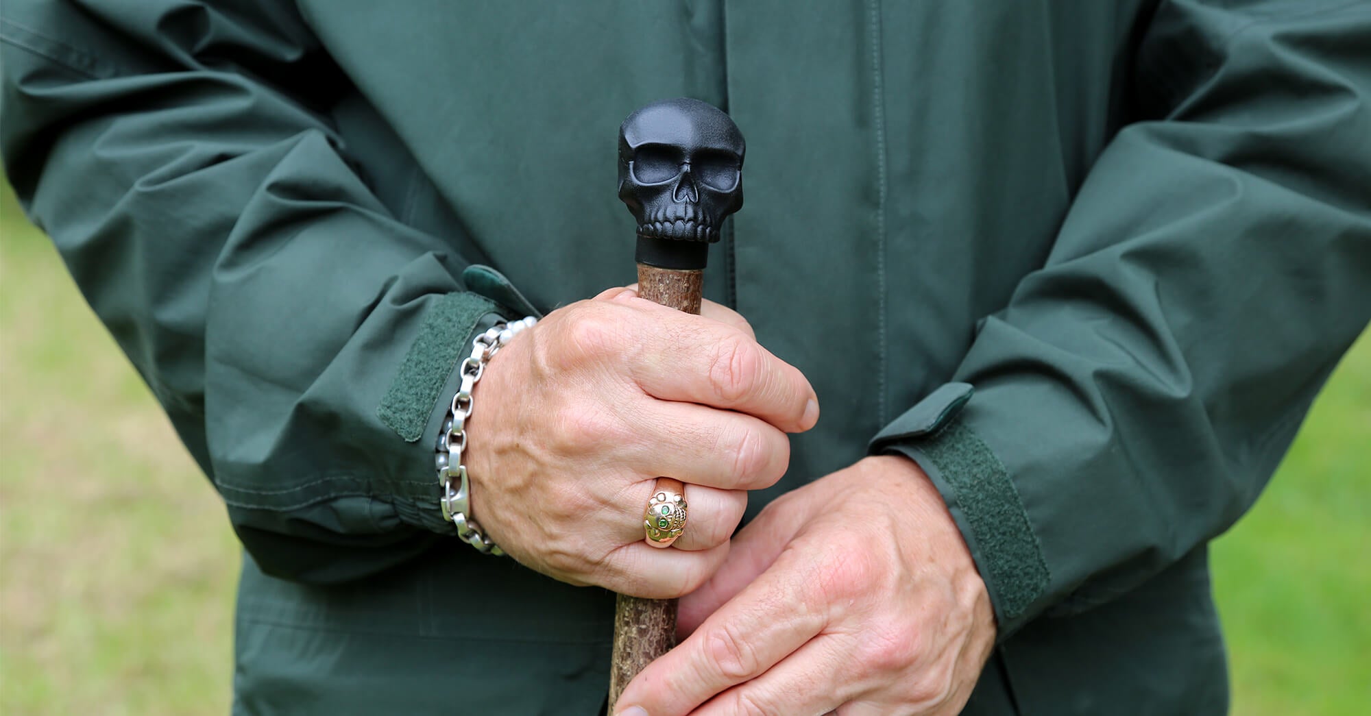 Hands wearing Stephen Einhorn rings and bracelet holding a skull-topped sustainable walking stick, Earthwatch Europe Tiny Forest collaboration