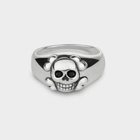 A close up of a smiling skull ring in silver